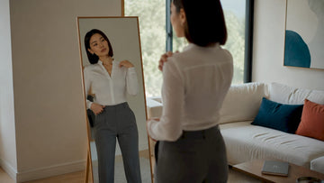 Woman assessing fit of minimalist outfit in mirror