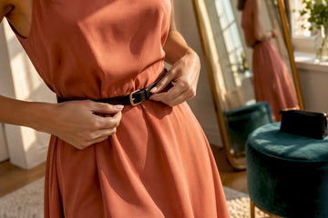 Cropped hands fastening belt over dress waist